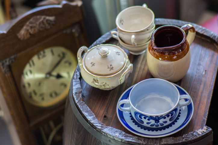 Assorted antiques on display, teacups and clock.  